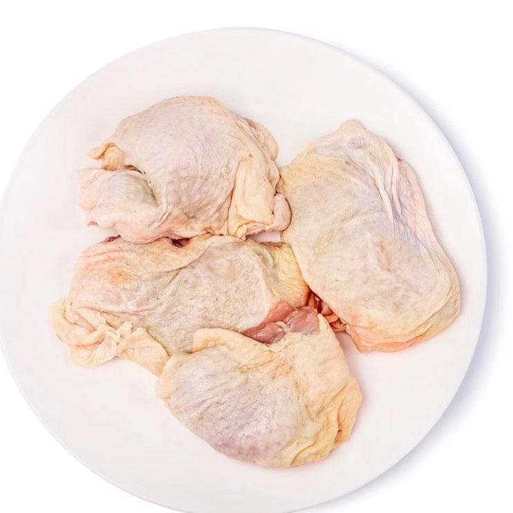 Raw chicken thighs on a white plate